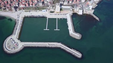Küçük, yeni inşa edilmiş bir tatil köyünün kuş bakışı manzarası - Pomorie yarımadası, büyük, tuzlu, sakin Karadeniz 'de birçok farklı modern tekne ve tekne. UHD 4K video gerçek zamanlı