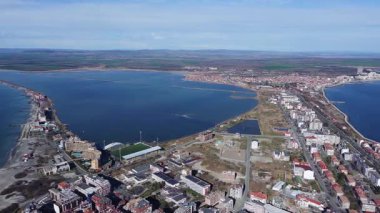 Bulgaristan 'ın kayalık yarımadasında bulunan ve büyük mavi, tuzlu Karadeniz tarafından turlanan küçük ve yoğun nüfuslu Pomorie kasabasına kuş bakışı bir bakış. UHD 4K video gerçek zamanlı