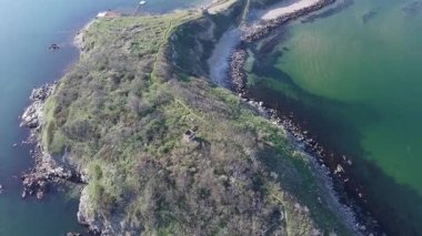 Bulgaristan 'ın açık mavi gökyüzü altında, sessiz turkuaz şeffaf Karadeniz ile çevrili, yabani çimenler ve otellerle kaplı kayalık kumlu dar sahillerin yükseklik ve yanından manzaraya bak. UHD 4K video gerçek zamanlı