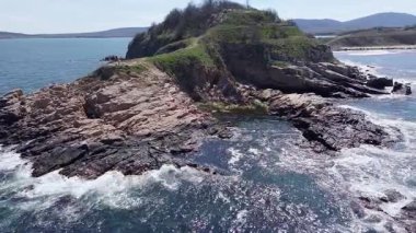 Kuşlar, açık mavi, güneşli bir günde açık mavi bir gökyüzünün altında Karadeniz 'in mavi dalgalı yüzeyindeki kayalık, ıslak bir çıkıntıya bakar ve yan bakar. UHD 4K video gerçek zamanlı