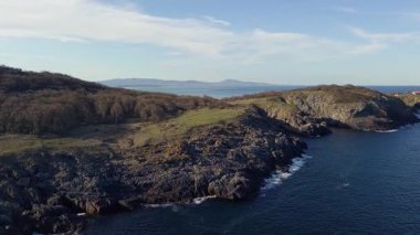 Bulgaristan 'ın parlak güneşli akşam günbatımına karşı sakin, mavi yansıtıcı Karadeniz ve eski karanlık kayalık taşlarla kaplı deniz manzarası. UHD 4K video gerçek zamanlı