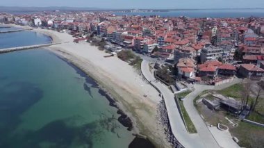 Bulgaristan 'ın kayalık yarımadasında bulunan ve büyük mavi, tuzlu Karadeniz tarafından turlanan küçük ve yoğun nüfuslu Pomorie kasabasına kuş bakışı bir bakış. UHD 4K video gerçek zamanlı