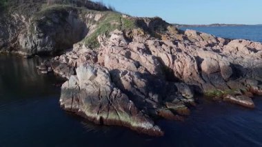 Bulgaristan 'ın parlak güneşli akşam günbatımına karşı sakin, mavi yansıtıcı Karadeniz ve eski karanlık kayalık taşlarla kaplı deniz manzarası. UHD 4K video gerçek zamanlı