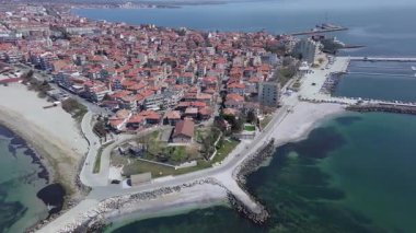 Bulgaristan 'ın kayalık yarımadasında bulunan ve büyük mavi, tuzlu Karadeniz tarafından turlanan küçük ve yoğun nüfuslu Pomorie kasabasına kuş bakışı bir bakış. UHD 4K video gerçek zamanlı