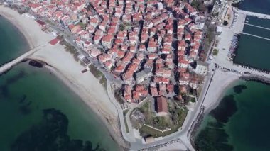 Küçük, yeni inşa edilmiş bir tatil köyünün kuş bakışı manzarası - Pomorie yarımadası, büyük, tuzlu, sakin Karadeniz 'de birçok farklı modern tekne ve tekne. UHD 4K video gerçek zamanlı