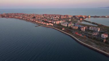 Bulgaristan 'ın kayalık yarımadasında bulunan ve büyük mavi, tuzlu Karadeniz tarafından turlanan küçük ve yoğun nüfuslu Pomorie kasabasına kuş bakışı bir bakış. UHD 4K video gerçek zamanlı