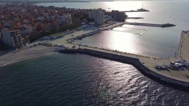 Küçük, yeni inşa edilmiş bir tatil köyünün kuş bakışı manzarası - Pomorie yarımadası, büyük, tuzlu, sakin Karadeniz 'de birçok farklı modern tekne ve tekne. UHD 4K video gerçek zamanlı