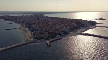 Bulgaristan 'ın kayalık yarımadasında bulunan ve büyük mavi, tuzlu Karadeniz tarafından turlanan küçük ve yoğun nüfuslu Pomorie kasabasına kuş bakışı bir bakış. UHD 4K video gerçek zamanlı