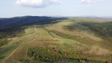 Birds eye view of spring blooming green meadows and wooded hilly slopes of the Balkan Mountains, under the light of a bright cloudy warm day in the country of Bulgaria. UHD 4K video realtime