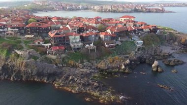 Birds eye view of the modern historic small town of Sozopol with a variety of cozy seaside houses and small sea spring boats, near the calm deep rippled Black Sea. UHD 4K video realtime