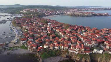 Birds eye view of the modern historic small town of Sozopol with a variety of cozy seaside houses and small sea spring boats, near the calm deep rippled Black Sea. UHD 4K video realtime