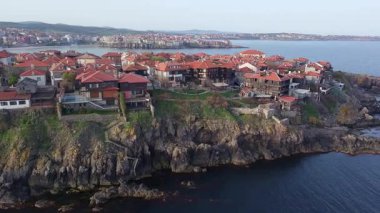 Birds eye view of the modern historic small town of Sozopol with a variety of cozy seaside houses and small sea spring boats, near the calm deep rippled Black Sea. UHD 4K video realtime