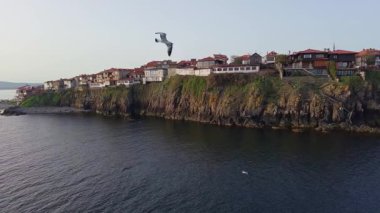 Birds eye view of the modern historic small town of Sozopol with a variety of cozy seaside houses and small sea spring boats, near the calm deep rippled Black Sea. UHD 4K video realtime
