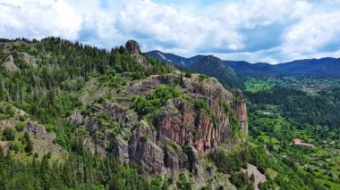 View from high rock to old village town Smolyan with green meadows for cattle walking and houses, between mountain range of Rhodope Mountains sheltered by spruce forests. UHD 4K video realtime