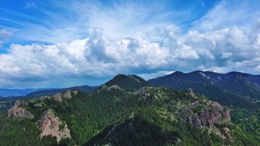 View from high rock to old village town Smolyan with green meadows for cattle walking and houses, between mountain range of Rhodope Mountains sheltered by spruce forests. UHD 4K video realtime