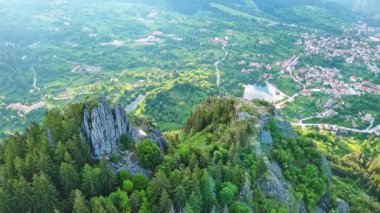View from high rock to old village town Smolyan with green meadows for cattle walking and houses, between mountain range of Rhodope Mountains sheltered by spruce forests. UHD 4K video realtime
