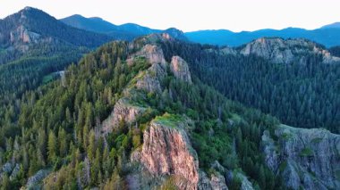 High rocky wild mountain range of Rhodope Mountains covered with green vegetation, against backdrop of mountain valley covered with dense dark spruce forests and blue cloudy sky. UHD 4K video realtime