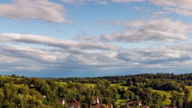 Dinamik bulutlar yemyeşil bir arazi ve bu yüksek açılı 4K UHD hızlandırılmış küçük bir kasaba boyunca sürükleniyor..