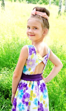 Yaz günü çayır üzerinde gülümseyen sevimli küçük kız