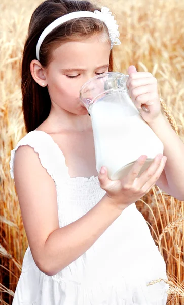 Schattig meisje consumptiemelk op gebied van tarwe — Stockfoto