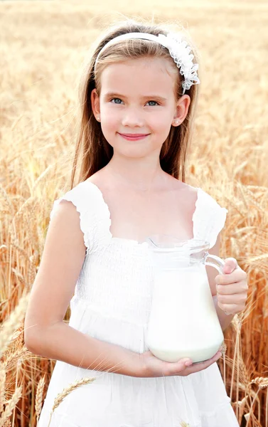 Adorable smiling little girl with milk on field of wheat — Stock Photo, Image