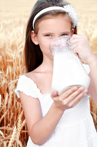 Adorable petite fille buvant du lait sur le champ de blé — Photo