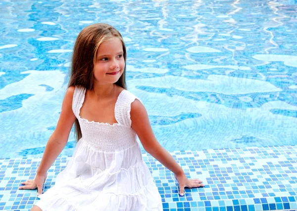 Adorable niña sonriente sentada cerca de la piscina —  Fotos de Stock