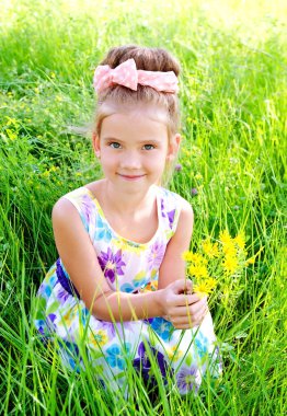 Yaz günü çayır üzerinde gülümseyen sevimli küçük kız