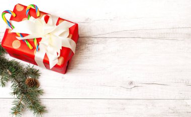 Noel arkaplanı. Yeni yıl kompozisyonu. Noel hediyesi, çam kozalakları, köknar dalları, şeker, tahta beyaz zeminde lolipop. Üst görünüm ve kopyalama alanı