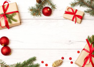 Noel çerçevesi ve geçmişi. Mutlu yıllar kompozisyonu. Noel hediyesi, kırmızı toplar, böğürtlenler, kozalaklar, tahta beyaz zeminde köknar dalları. Üst görünüm ve kopyalama alanı