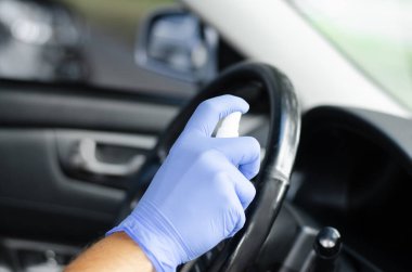 Adam arabasının tekerleğini ve salonunu dezenfekte ediyor. Koruyucu eldivenli bir erkek dezenfektan tutuyor. Dezenfeksiyon hijyeni ve koronavirüs konsepti 