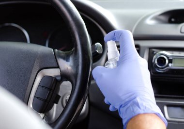 Adam arabasının tekerleğini ve salonunu dezenfekte ediyor. Koruyucu eldivenli bir erkek dezenfektan tutuyor. Dezenfeksiyon hijyeni ve koronavirüs konsepti 