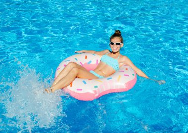 Plastik yüzükle havuzda yüzen tatlı küçük kız. Çocuk yaz tatilinde eğleniyor