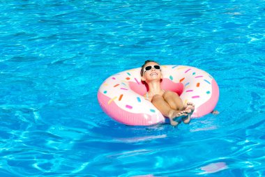Plastik yüzükle havuzda yüzen tatlı küçük kız. Çocuk yaz tatilinde eğleniyor