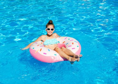 Plastik yüzükle havuzda yüzen tatlı küçük kız. Çocuk yaz tatilinde eğleniyor