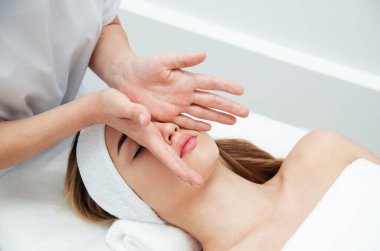 Güzellik uzmanı kadının yüzüne masaj yapıyor. Çekici kız yüz bakımı ve masaj yaptırıyor. Genç kadın yalan söylüyor ve dinleniyor. Güzel kadın yüzü cilt terapisi görüyor.