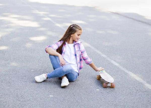 スケートボードに座ってかわいい女の子の子供を笑顔 屋外で夏の日にペニーボードでプレティーン — ストック写真