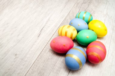 Ahşap bir arka planda renkli el yapımı Paskalya yumurtaları. Üst görünüm ve kopyalama alanı