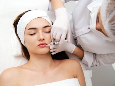 Kadın kozmetik yapıyor. Enjeksiyon. Güzellik iğneleri ve kozmetoloji. Güzellik salonundaki genç kadın. Yakın plan. Estetik cerrahi ve güzellik tedavisi.