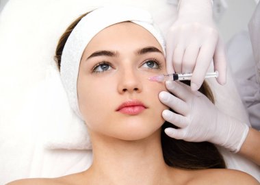 Kadın kozmetik yapıyor. Enjeksiyon. Güzellik iğneleri ve kozmetoloji. Güzellik salonundaki genç kadın. Yakın plan. Estetik cerrahi ve güzellik tedavisi.