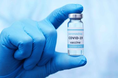 Doktor ya da koruyucu eldivenlerin içinde COVID virüsü için nCoV Coronavirus aşısı bulunan ampul tüp tutuyorlar. Coronavirus ve tıbbi konsept.