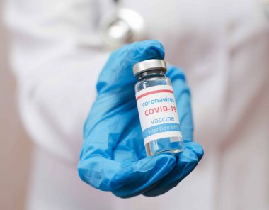 Doktor ya da koruyucu eldivenlerin içinde COVID virüsü için nCoV Coronavirus aşısı bulunan ampul tüp tutuyorlar. Coronavirus ve tıbbi konsept.