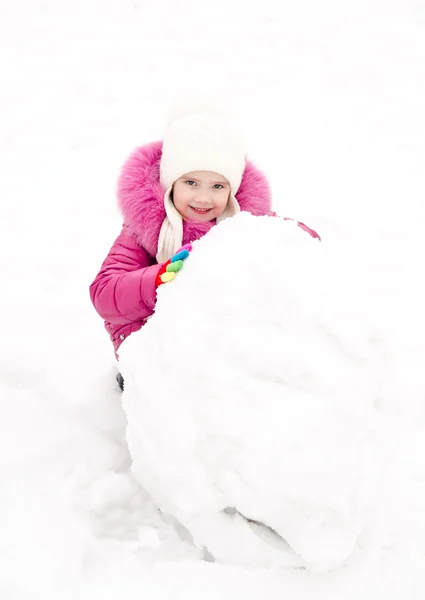 Mignon sourire petite fille fait bonhomme de neige dans la journée d'hiver — Photo