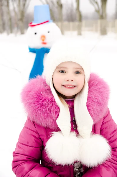 Retrato de niña sonriente con muñeco de nieve en el día de invierno —  Fotos de Stock