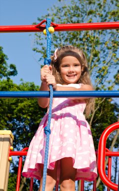 oyun alanı ekipmanı üzerinde oynarken küçük kız gülümseyerek 