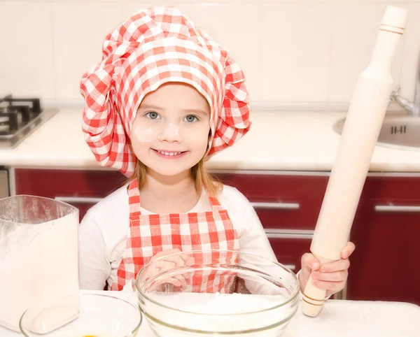 Leende liten flicka med kocken hatt och kavel — Stockfoto