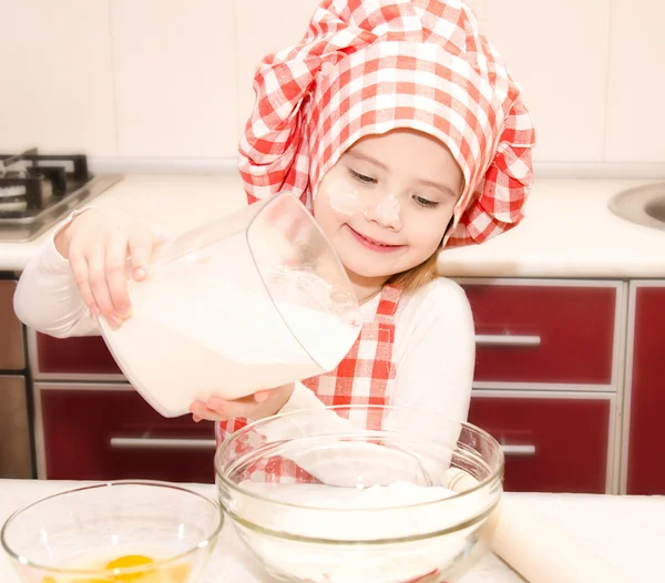 Leende liten flicka med kock hat lägga mjöl för bakning cookies — Stockfoto