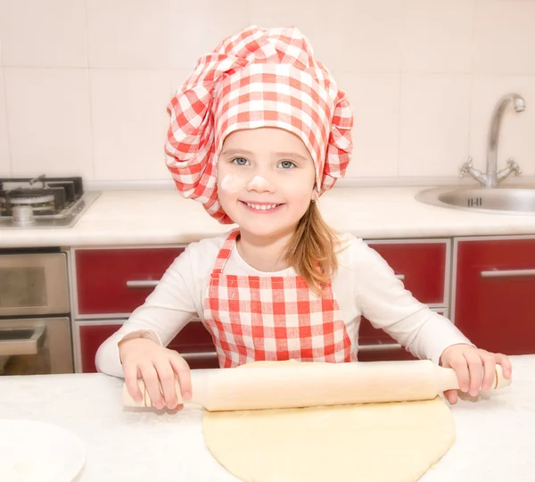 Счастливая маленькая девочка в шляпе шеф-повара катит тесто — стоковое фото