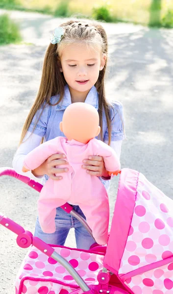 Carino bambina che gioca con la sua carrozza giocattolo — Foto Stock