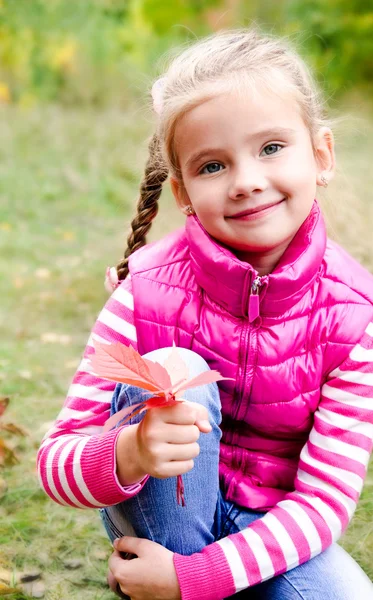 Adorable smiling little girl sitting on grass — Stock Photo, Image